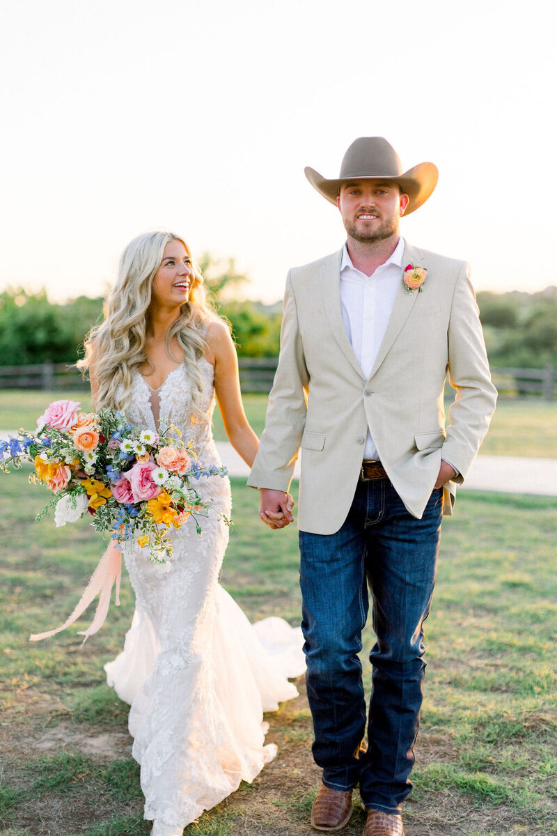 Bride and groom walking hand-in-hand with garden-inspired bouquet
