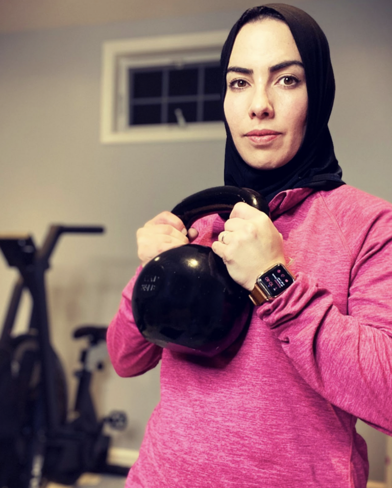 Photo of a hijabi woman wearing a pink longsleeve while holding a kettle bell
