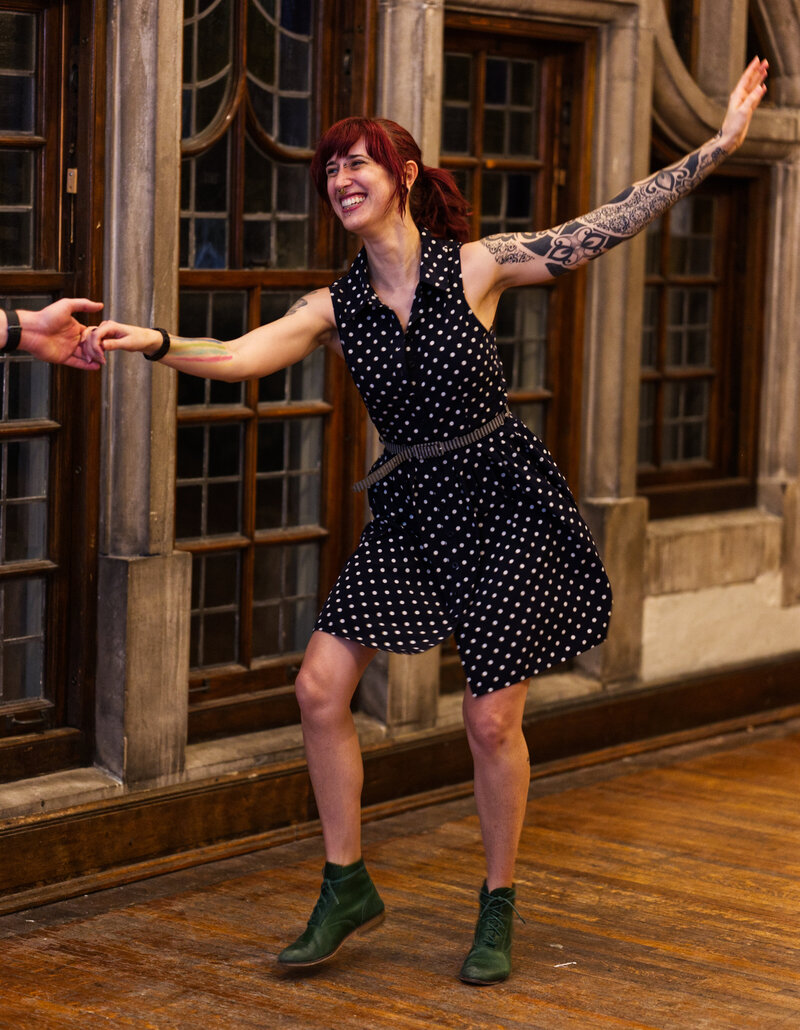 a woman in a polka dot dress and green boots follows lindy hop