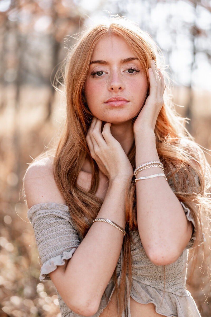 Senior girl gazing at camera with her hands on each side of her face in Farmington, Missouri. 