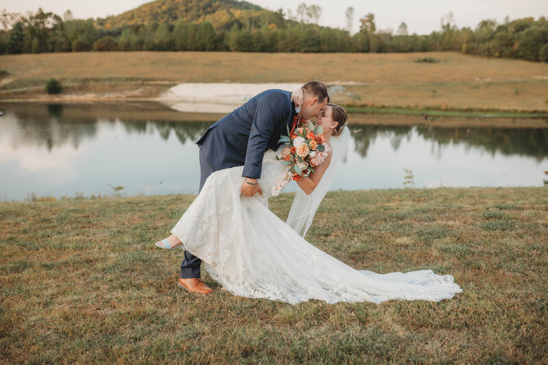 Groom dips bride by a lake at Lake Mountain Manor in Princeton, West Virginia.