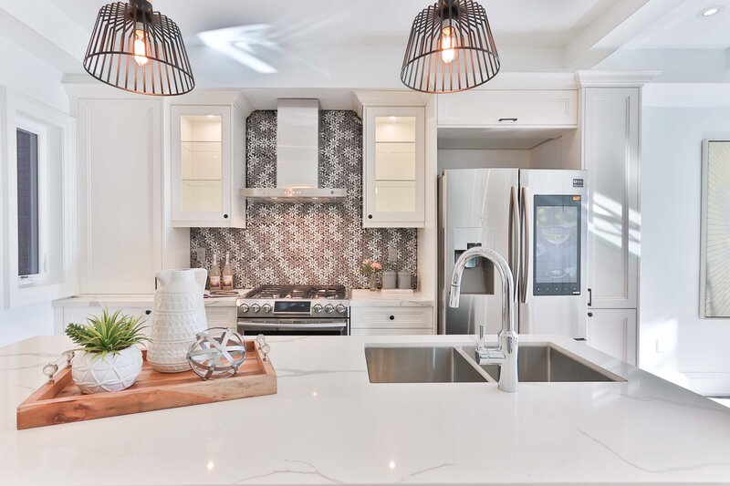 Kitchen with white cabinets, pendant lights, and tile backsplash.
