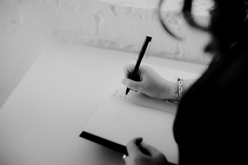 A close-up of a hand writing a to-do list in a notebook, representing actionable feedback and strategies offered by KP Virtual Assistance for photographers to improve their workflows
