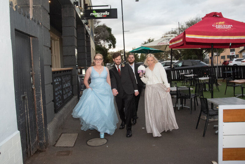 location in Williamstown, Victoria. Wedding  crew striking a pose whilst walking to reception down main street.