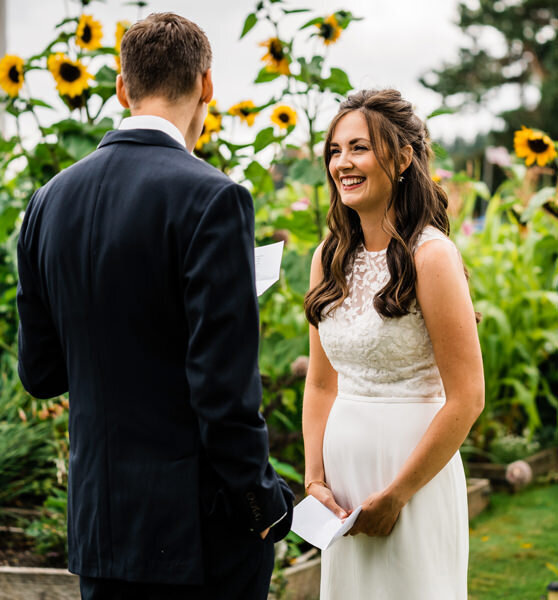 A bride listens to her groom say his vows in a sunflower garden on Camano Island