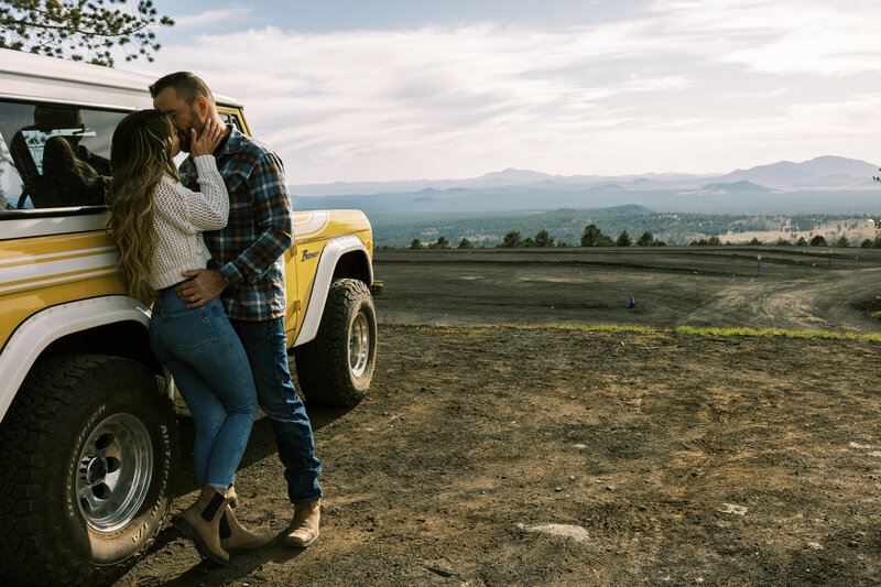couple kissing against vintage vehicle