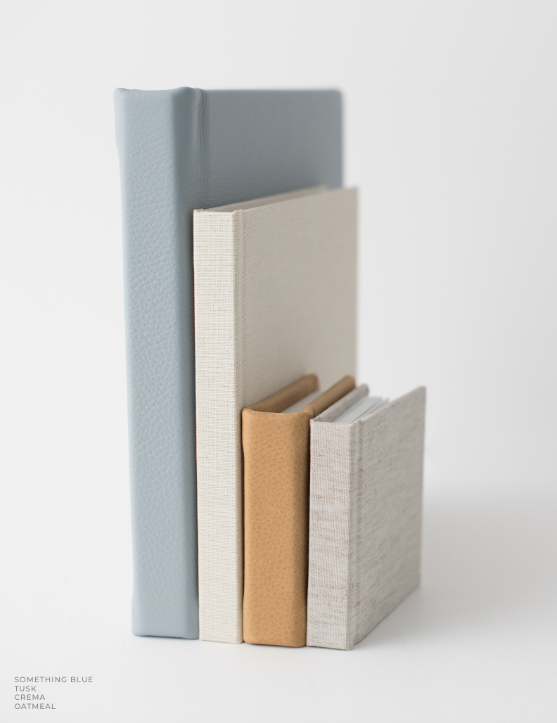 Four wedding albums of various sizes, in blue, cream, leather, and linen