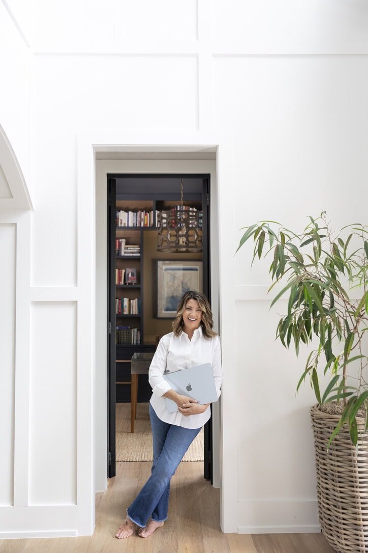woman standing in doorway of her office holding a laptop