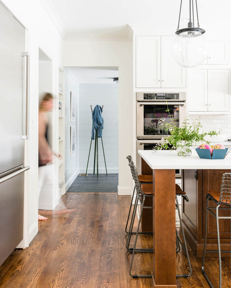Needham kitchen designer creates a white kitchen with a walnut island, modern stools, and new stained wood floors after a large-scale renovation in Needham, Massachusetts.