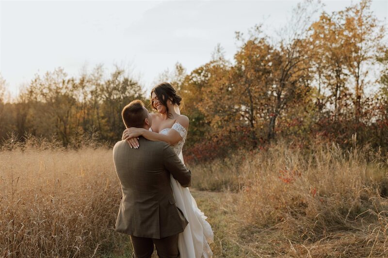 groom is lifting bride and spinning her in a field