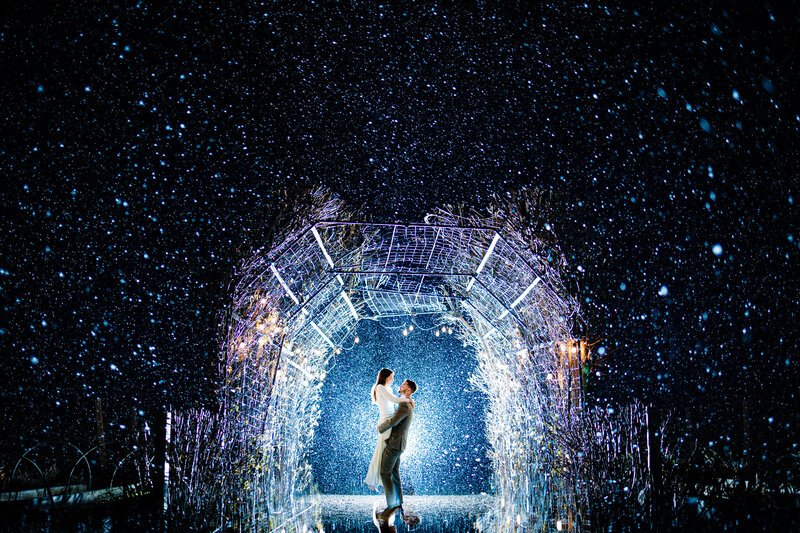 A groom lifting up the bride in a garden during a snow storm at night in Ann Arbor Michigan