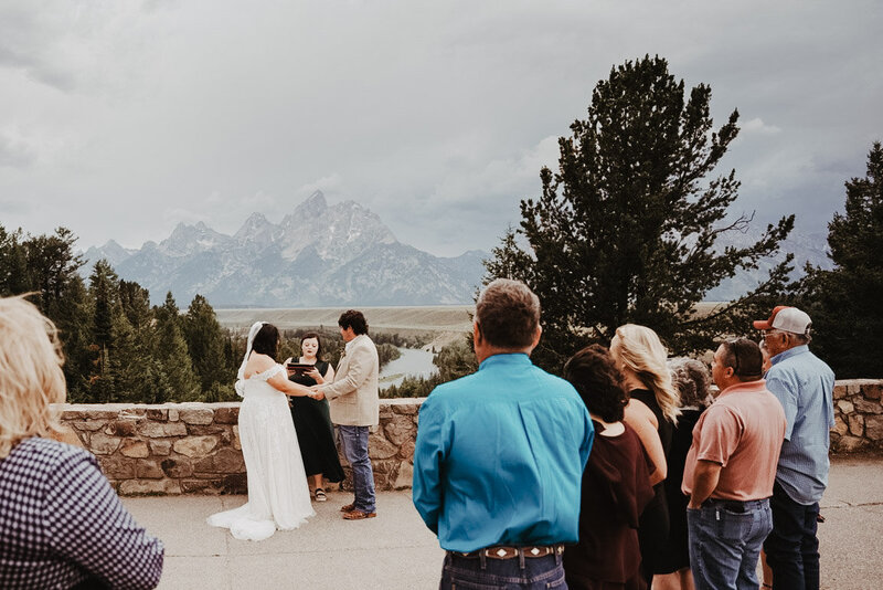 outdoor jackson hole wedding  ceremony with bride and groom holdin ghands during their vow ceremony at Snake River Turn out in the grand tetons