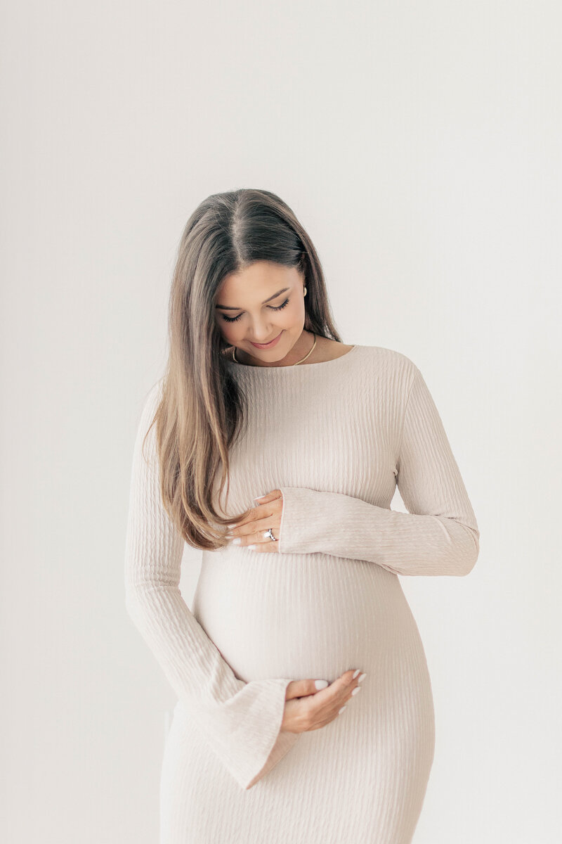 Maternity portrait of a mother-to-be cradling her belly as she tenderly sways in a Kansas City photography studio 