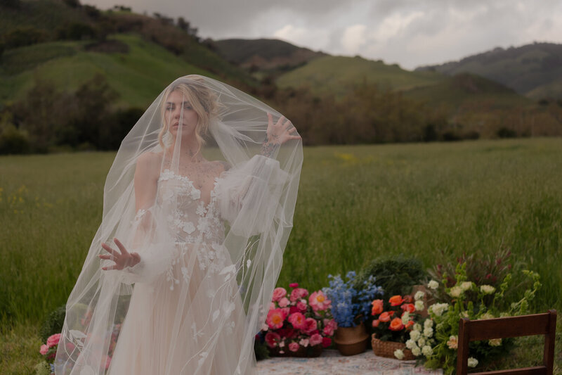 Elopement weddings photos bride under veil photo with flowers in back ground and green field in San Luis Obispo at Higuera Ranch