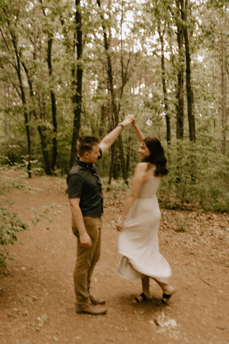 Blurry photo of a boy spinning a girl in a green forest