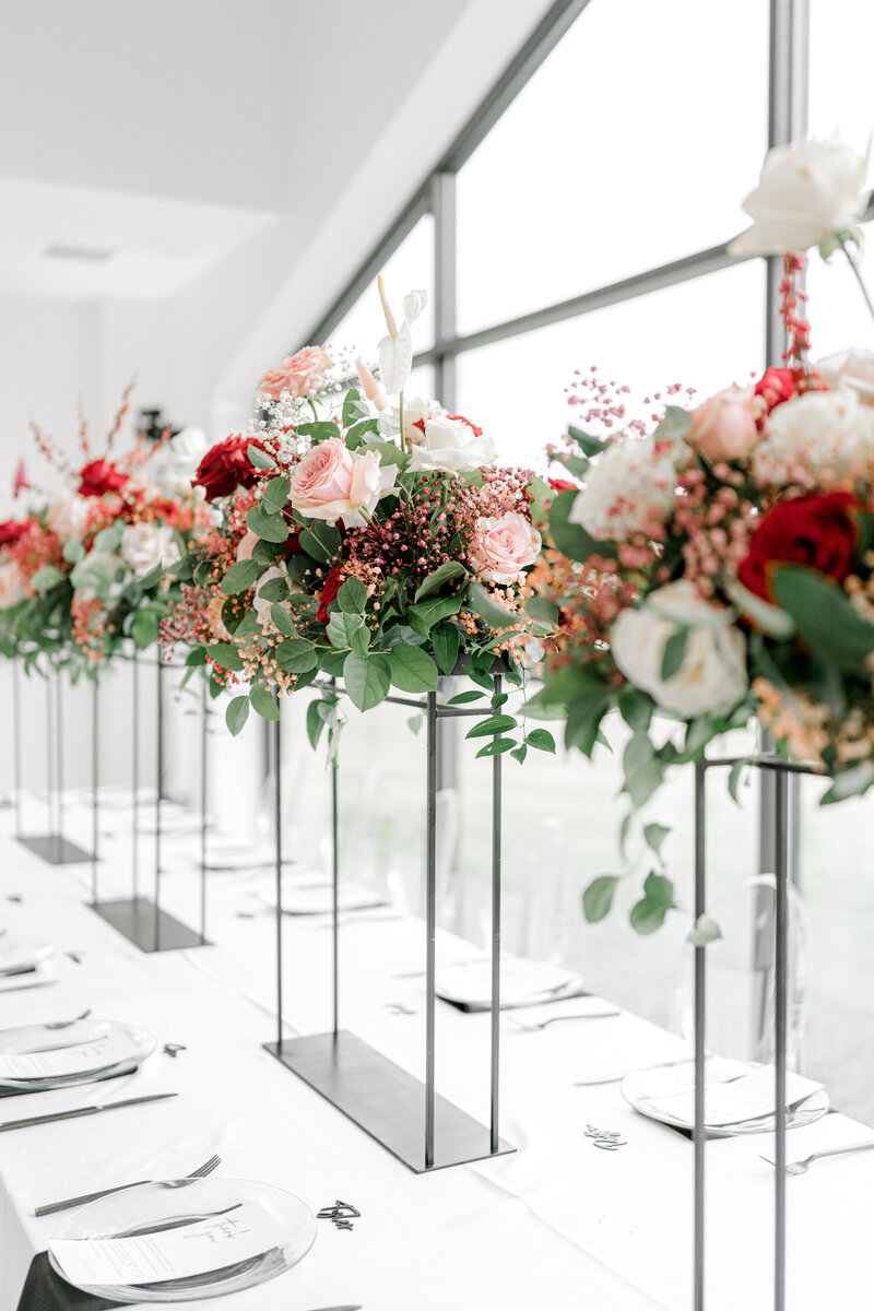 Pink, red, and white raised floral centerpieces on a white table
