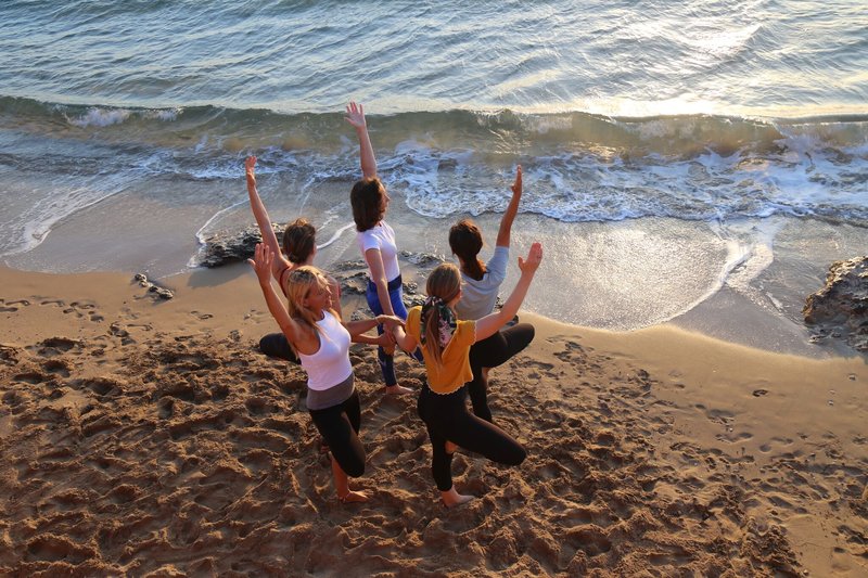 YTT graduates pose on the beach by the ocean in greece