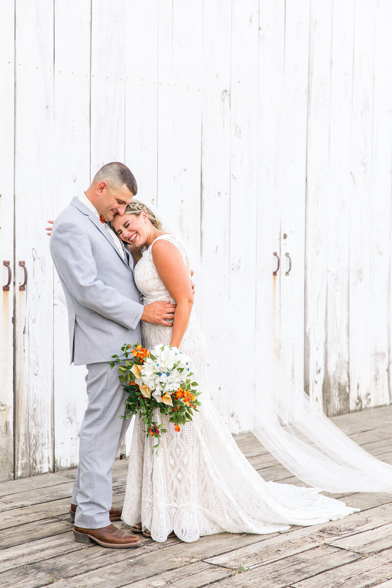 Newlywed couple posing in front of barn
