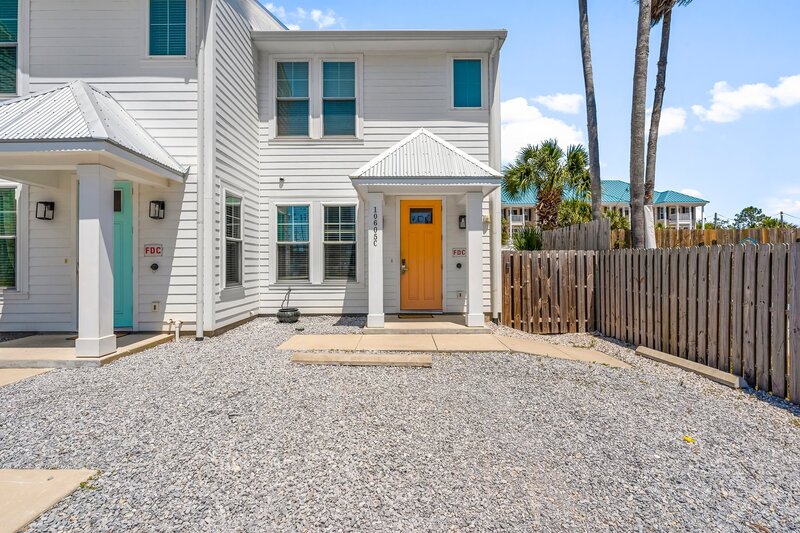 Bright orange front door welcoming you to 'Welcome to Paradise' in Panama City Beach—an eye-catching touch for your next vacation photo op.