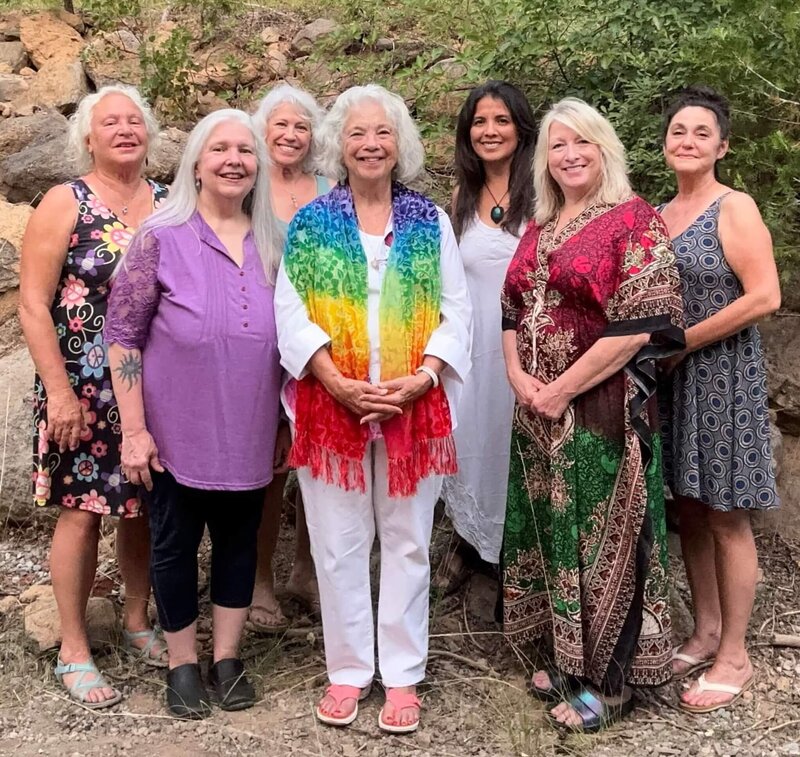 Samarah Grace in white clothing and rainbow scarf at outside reiki retreat with woman smiling