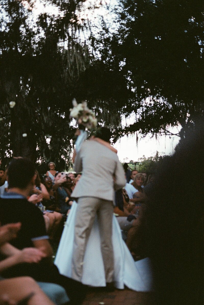 Bride and groom kissing in the aisle by 35mm film wedding photographer Noble Photo Co