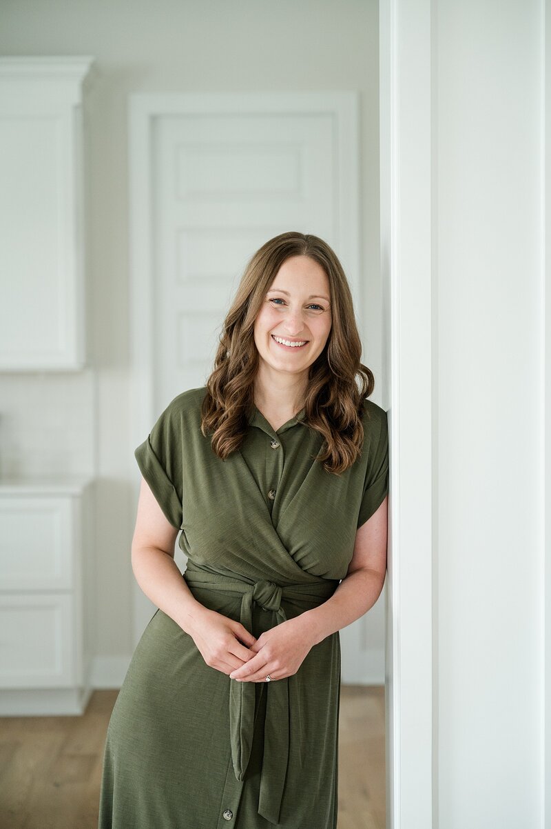 small business headshot with woman in a forrest green dress leaning on the door way for her brand photos with columbus photographer