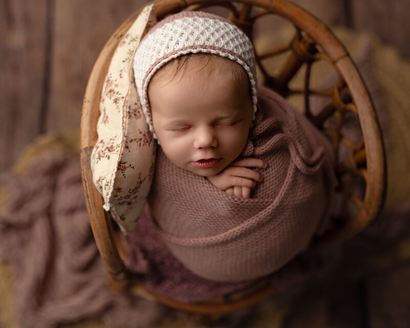 Timeless textures and sweet florals bring warmth to this newborn girl’s portrait in a vintage chair.