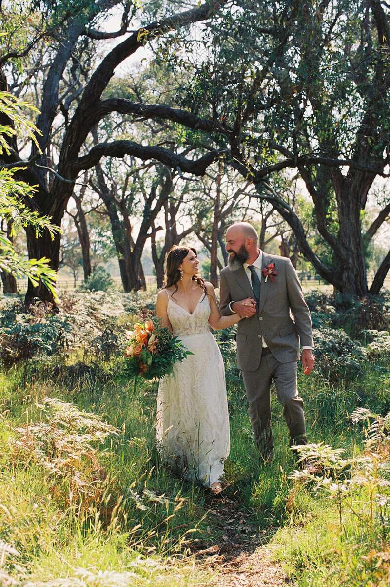 Bride and groom at ceremony on white stage under trees