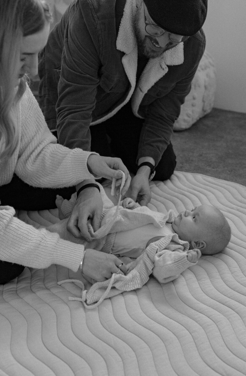 In home maternity photoshoot. Mother looking down and holding her pregnant belly. 