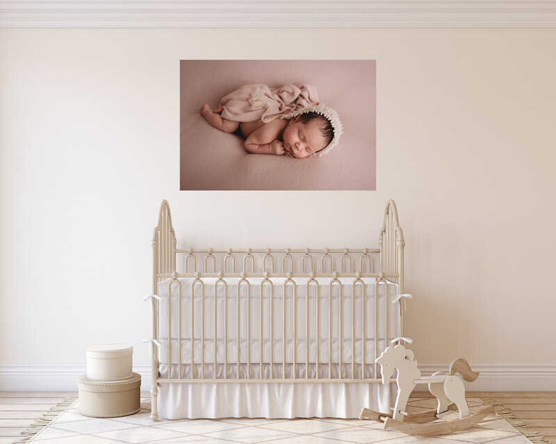 Atlanta, Georgia newborn photographer canvas artwork hanging in nursery with white walls and white furniture. Canvas artwork has image of newborn baby girl