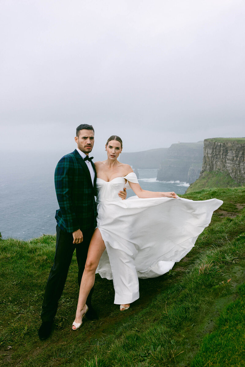 Couple posing for photos during their elopement at the top of the cliffs of Moher in Ireland