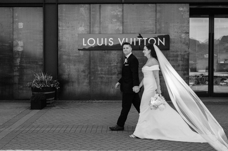 a bride and groom walk past louis vuitton on the waterfront in queenstown