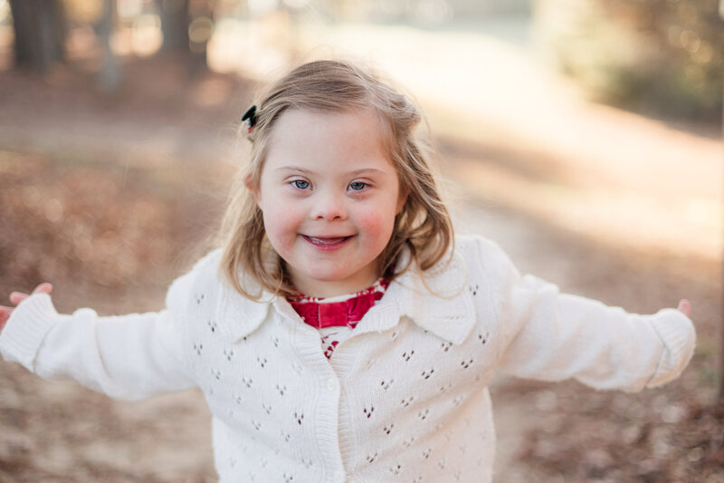 Group of females posed and smiling on a football field in graduation gowns.