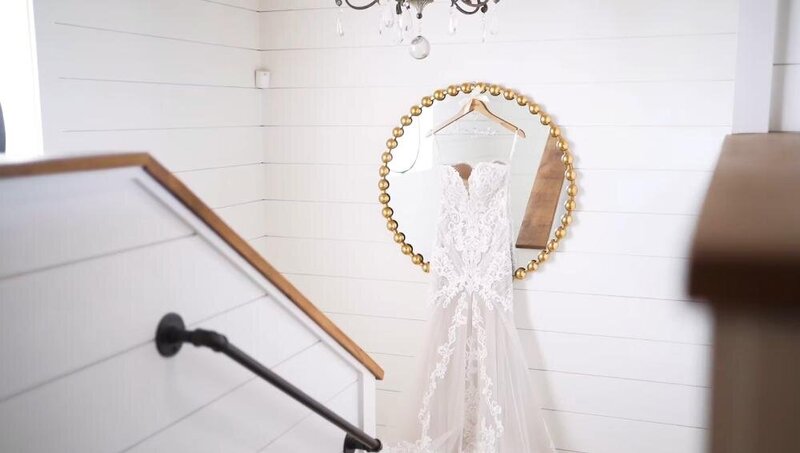 A wedding dress hanging on a mirror in a brightly lit room, captured by a Destination Wedding Photographer.