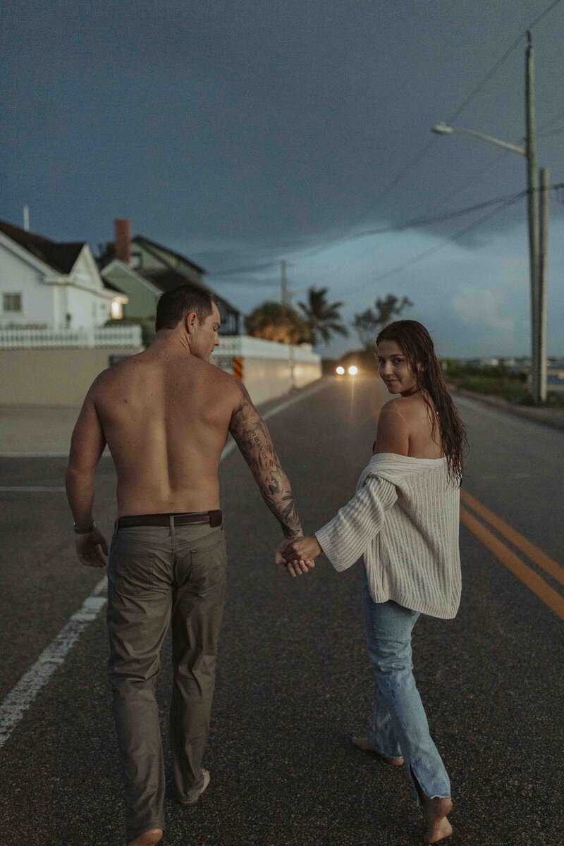 Couple holding hands walking down the street barefoot