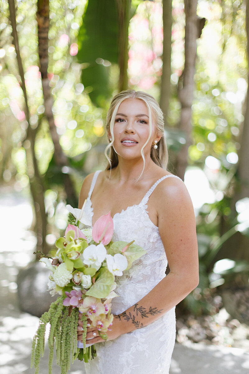Bride in white dress while holding a luscious tropical bouquet 