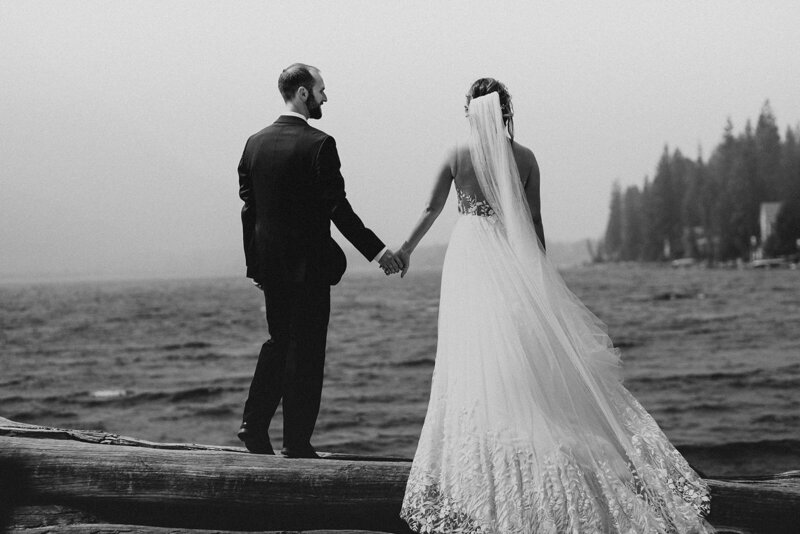 black and white image bride and groom holding hands on beach