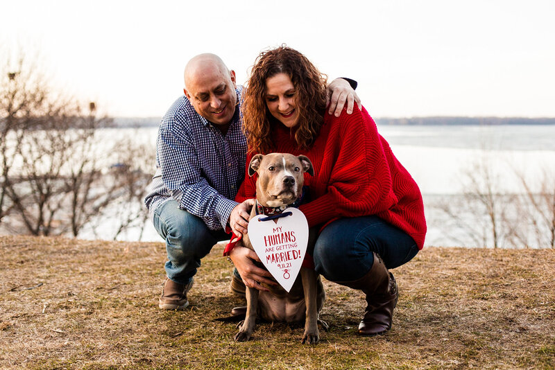 Erie PA couple poses with their dog wearing a save the date sign