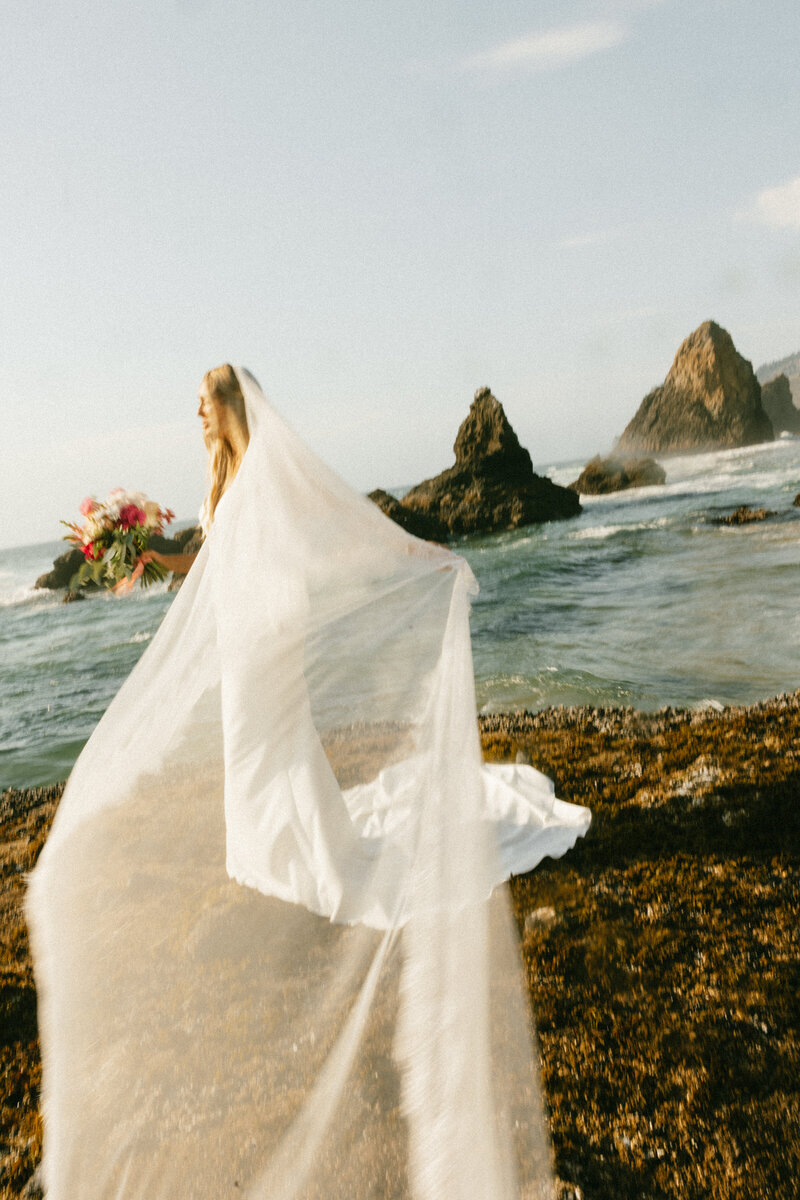 Groom in tan vest, blue tie, and pants sitting and hugging Bride