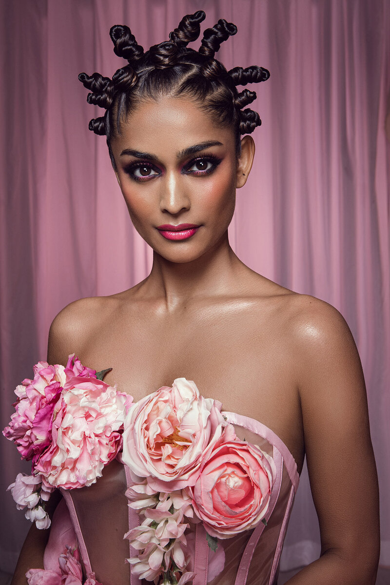 Elegant portrait of Alyssah in a pink floral gown, standing against a soft pink backdrop, captured by Ylva Erevall.