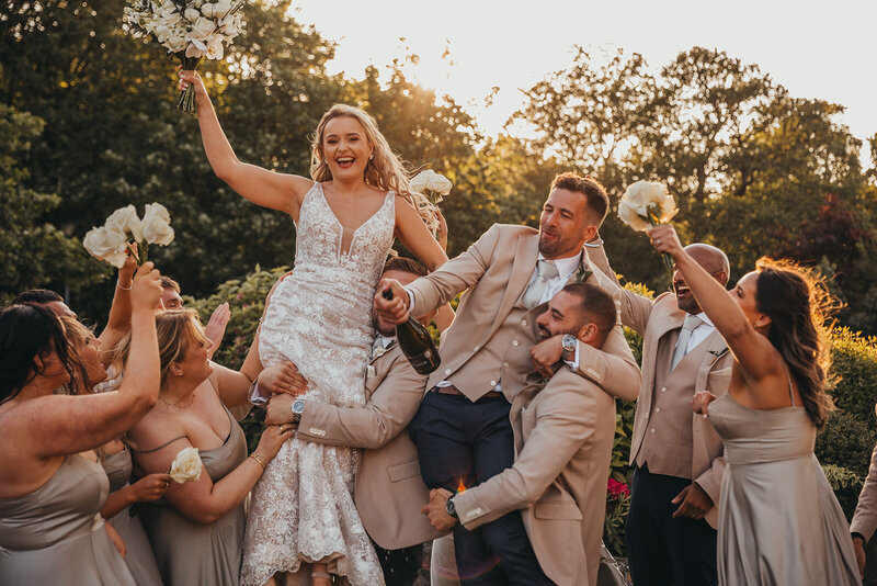 wedding party lifts bride and groom