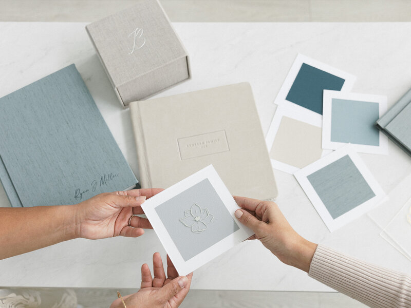Hands holding linen album cover swatches during custom artwork design consultation.