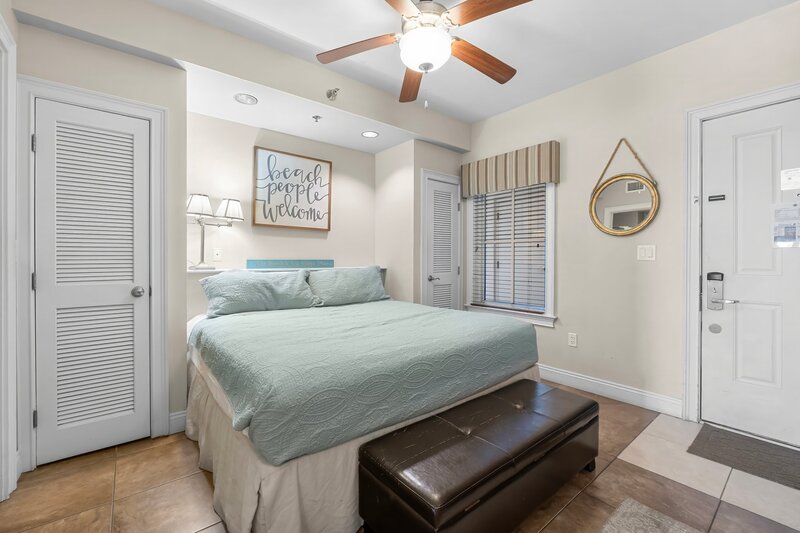teal coverlet on king bed and brown chest