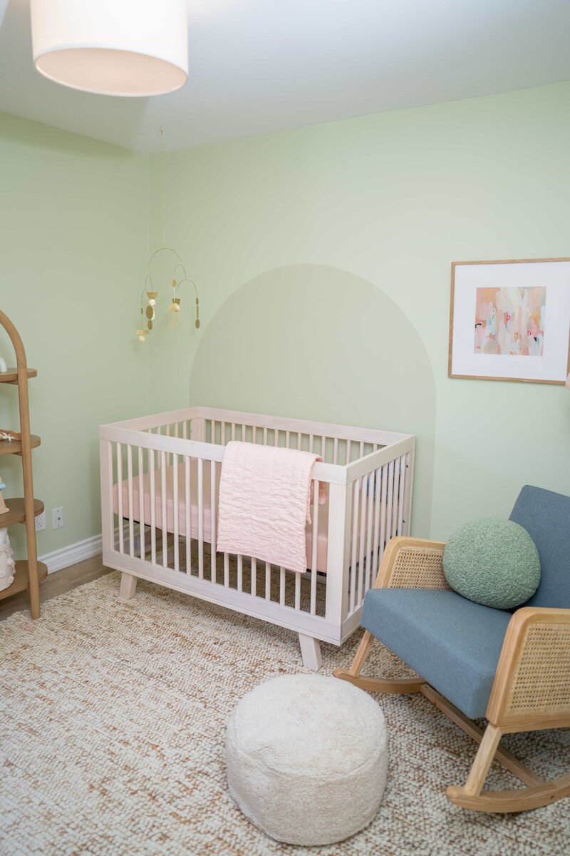 Crib and armchair in mint green nursery room