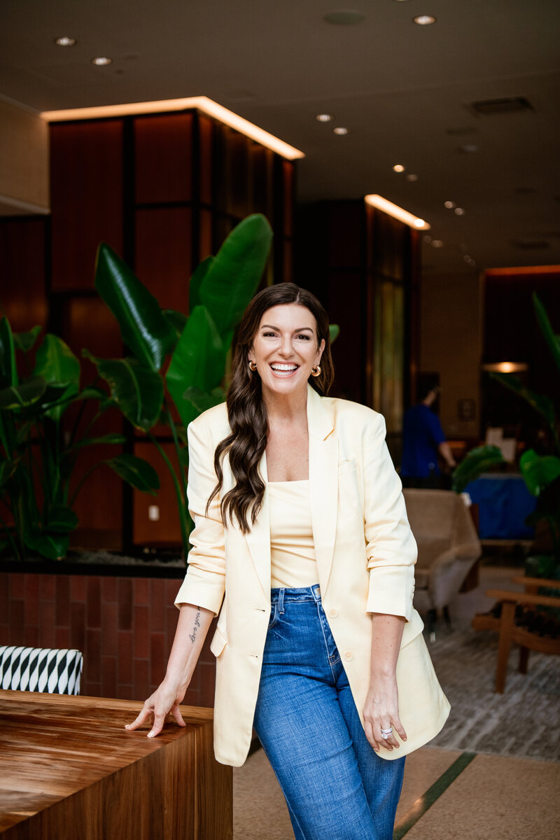 online marketing expert, Amy Porterfield in yellow blazer standing by desk