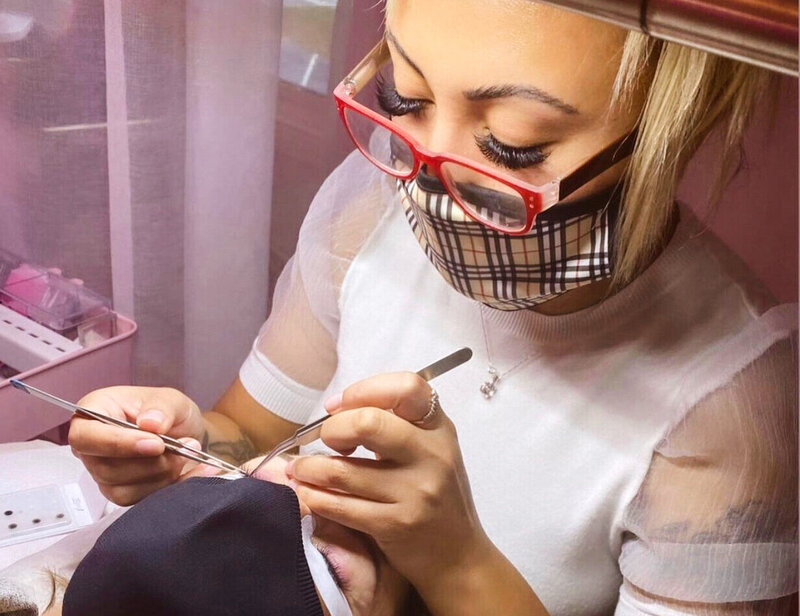 A lash technician working on a client