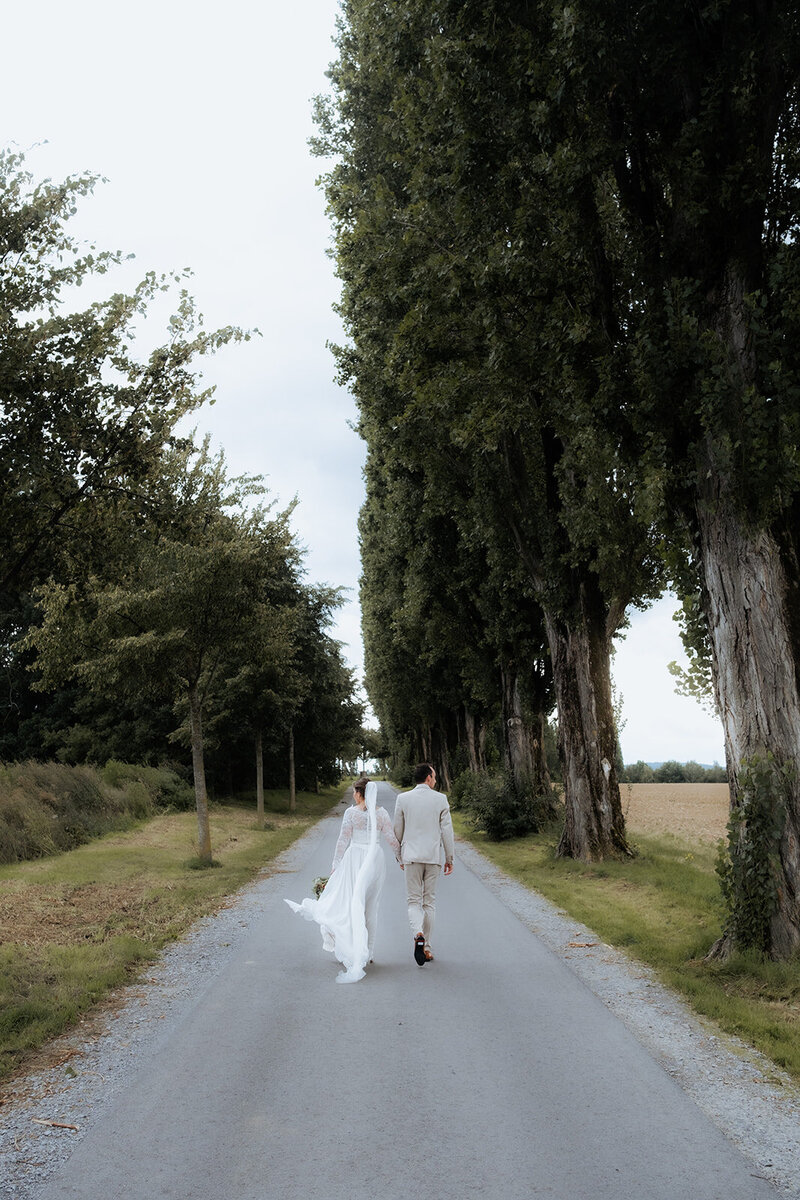 Braut und Bräutigam laufen die Pappelallee entlang