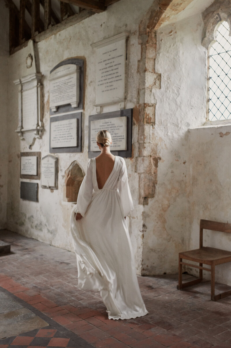 British designer silk long-sleeved wedding dress, bride wearing long, flowing, modern bridal gown in church