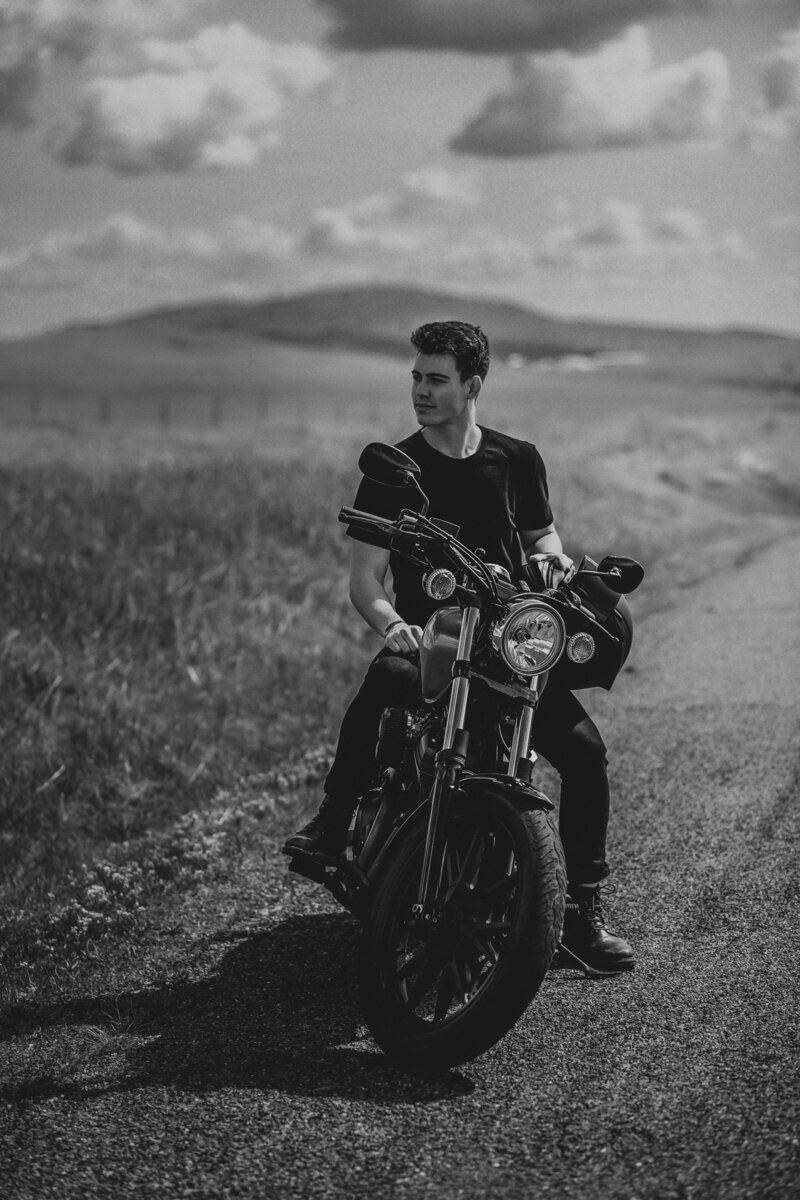 man sitting on a motorcycle on a dirt road