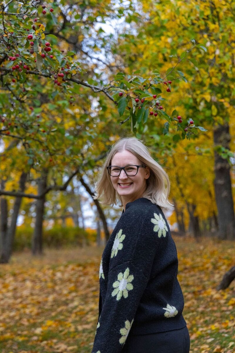 Jenny Moran walking on a leafy pathway with autumn leaves scattered on the ground.
